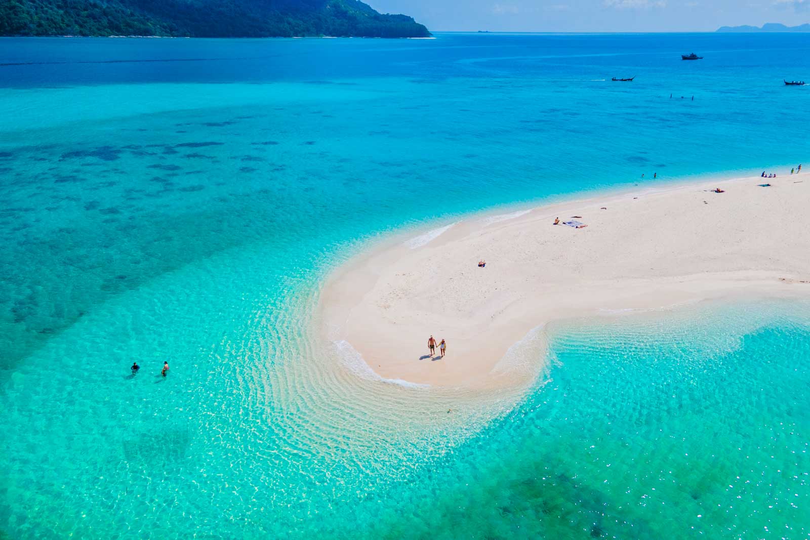 men and women walking on a sandbar in the ocean of Koh Lipe Southern Thailand during vacation.