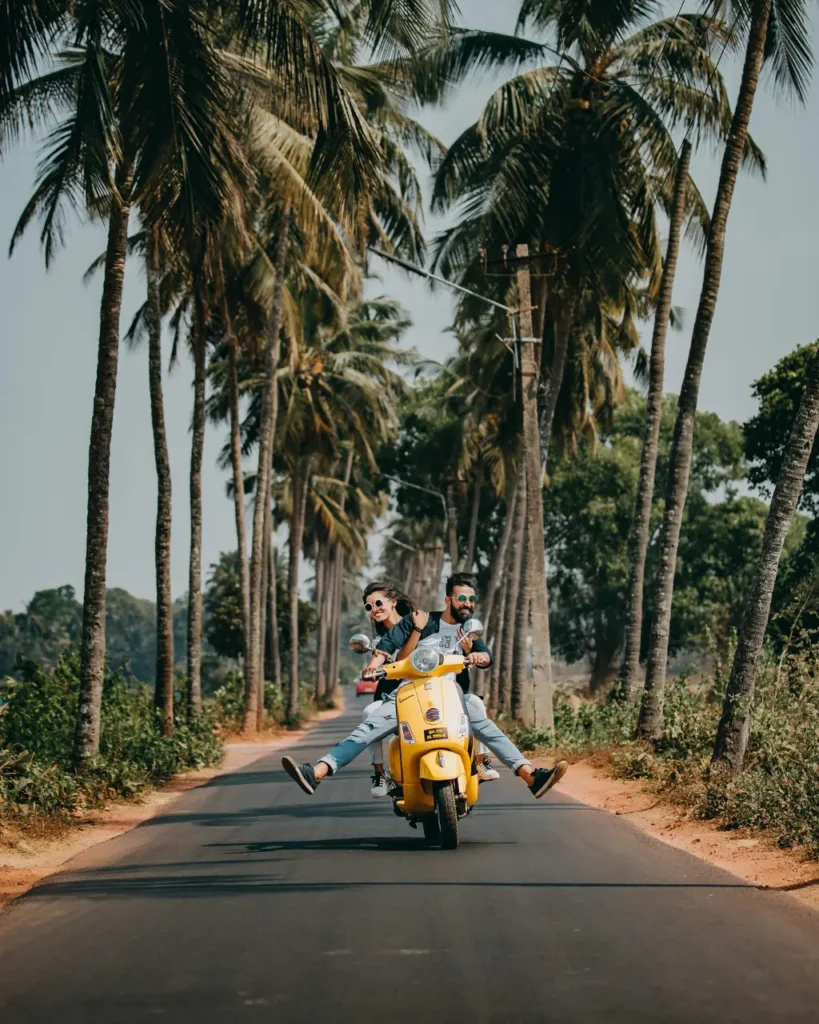 Zakochana para jadąca razem na skuterze po drodze otoczonej palmami