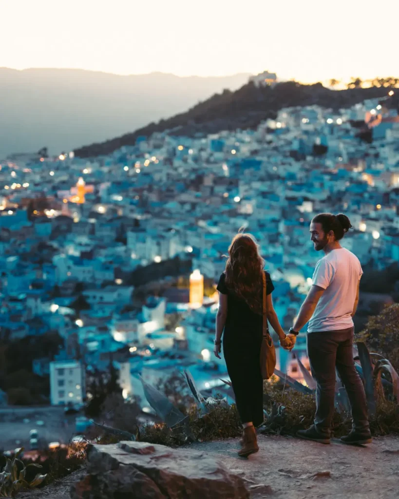 Para trzymająca się za ręce patrzy na greckie miasteczko na Santorini